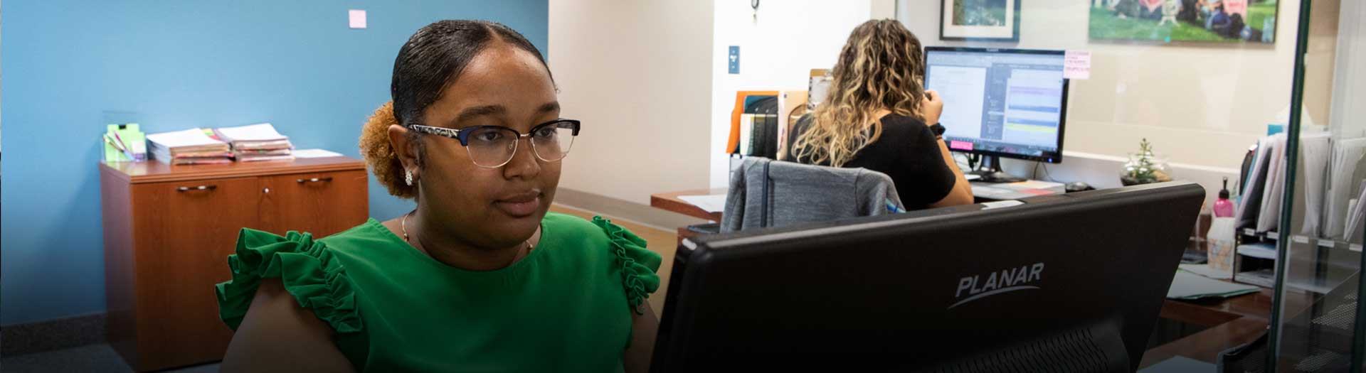 contact-us-banner Two women in an office at their computers