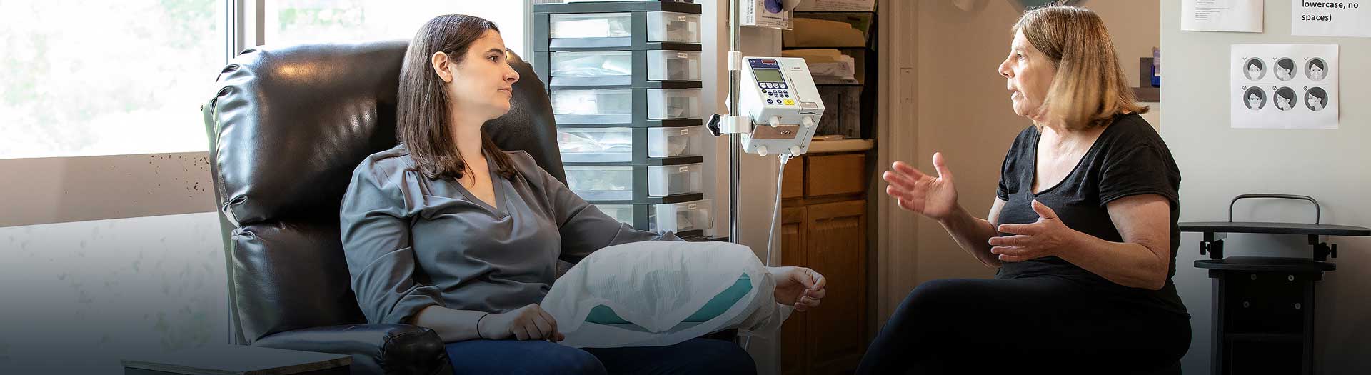 on-site-infusion-center-banner A woman using an infusion therapy and talking to a doctor.